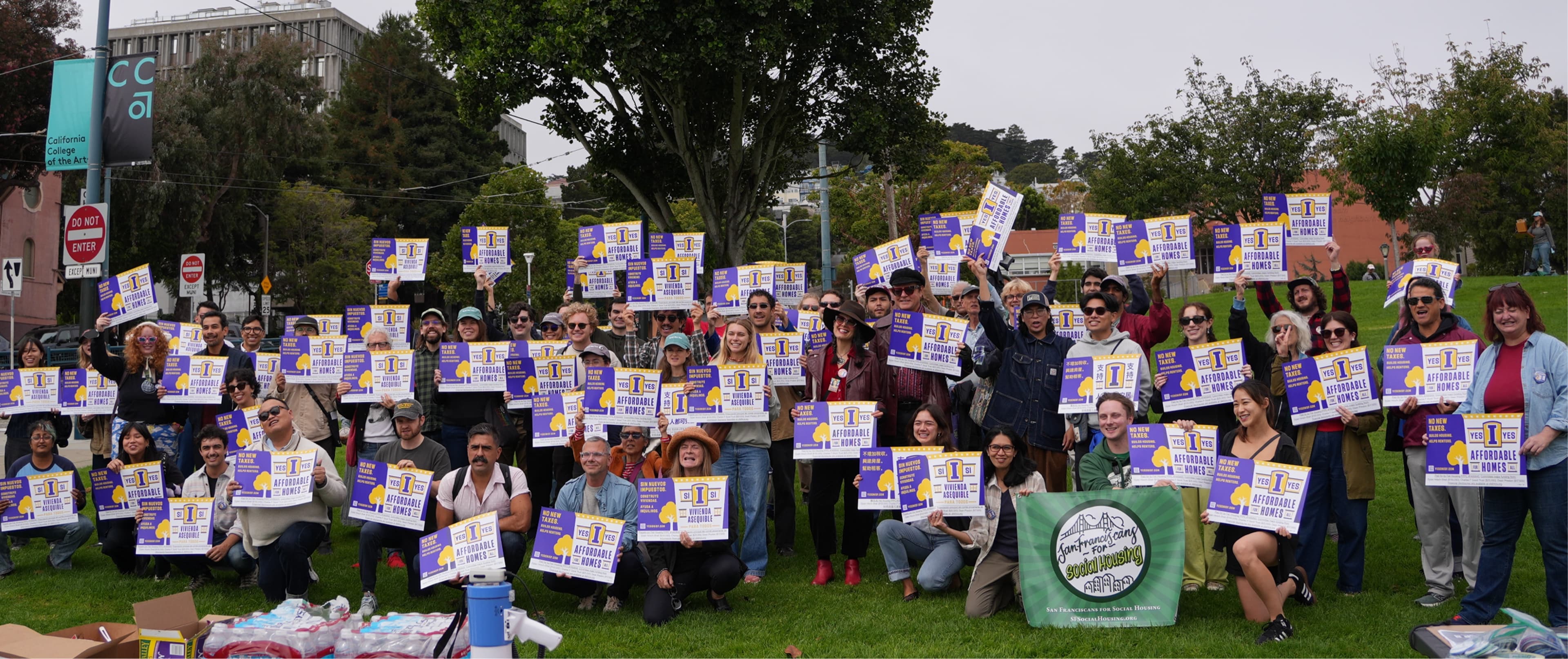 Supporters on a lawn holding Yes on Prop I signs at a San Franciscans for Social Housing campaign event
